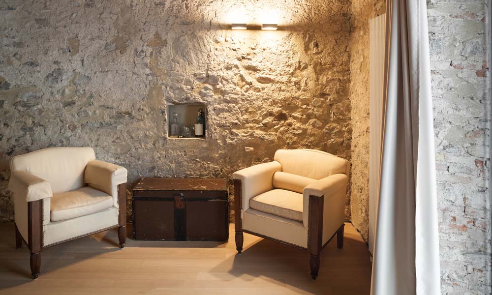 1. Wohnidee für Landhausmöbel: Rustikale Hartholz-Sessel in Weiß vor Natursteinwand