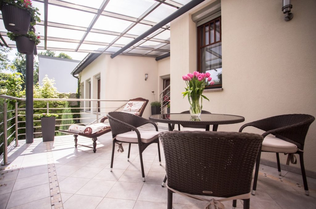 Gestaltet man den balkon als moderne Terrasse, können dort mediterrane Fliesen zum Einsatz kommen. Gegen überraschenden regen schützt das Glasdach.