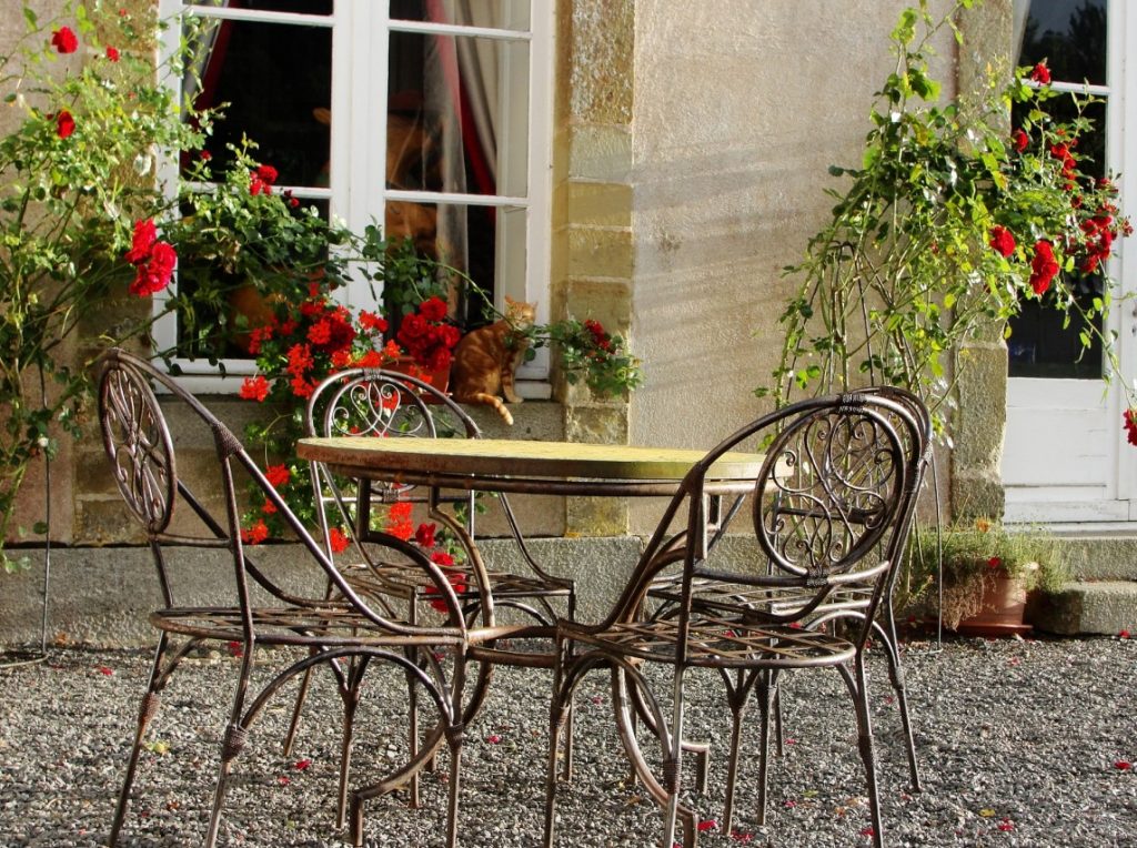 Tipp #2: Stahlrohr-Sitzmöbel auf Kies vor einem Rosenspalier wie vor einem französischen Chateau