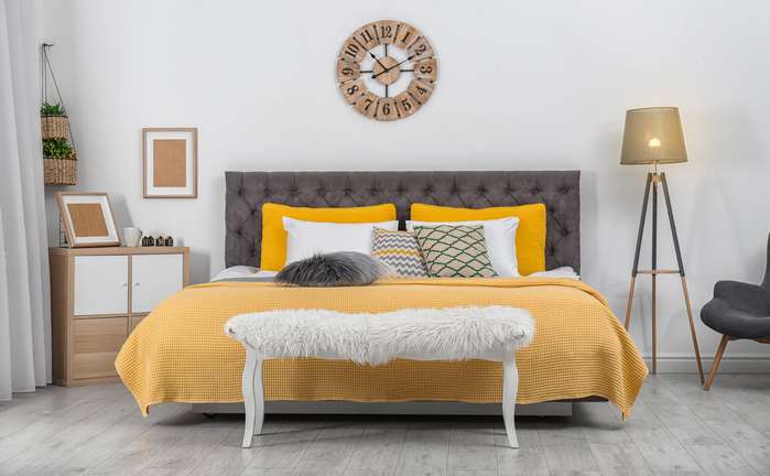 Ein graues Boxspringbett, gelbe Tagesdecke, goldene Dekoartikel so farbenfroh kann das Schlafzimmer aussehen. ( Foto: Adobe Stock - New Africa )