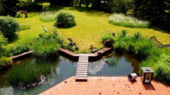 Ein großer Garten bietet dem Gartenliebhaber viele Gestaltungsmöglichkeiten. Auf der Fläche lassen sich viele Einzelwünsche als Szenen umsetzen, die beim Durchwandern Geschichten und Träume erleben lassen. Hier hat ein kleines Gewässer Einzug gehalten. Mit einer romantischen Brücke kann er in ein verträumtes Paradies führen. (Foto: AdobeStock - globetrotter1)